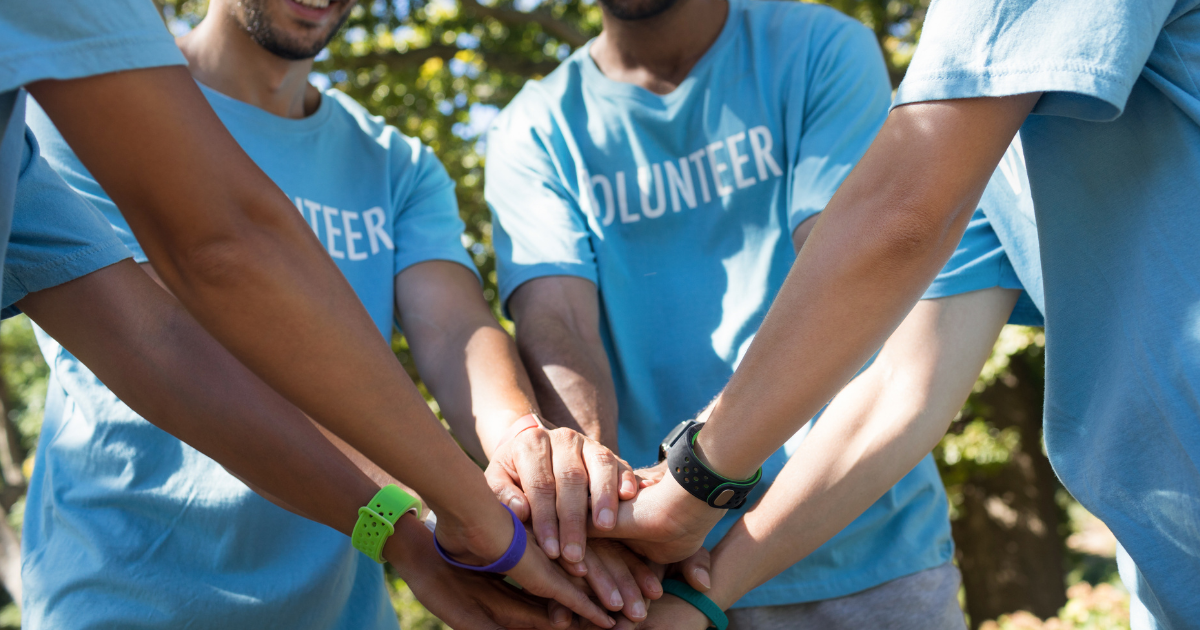 team of volunteers putting their hands into a circle