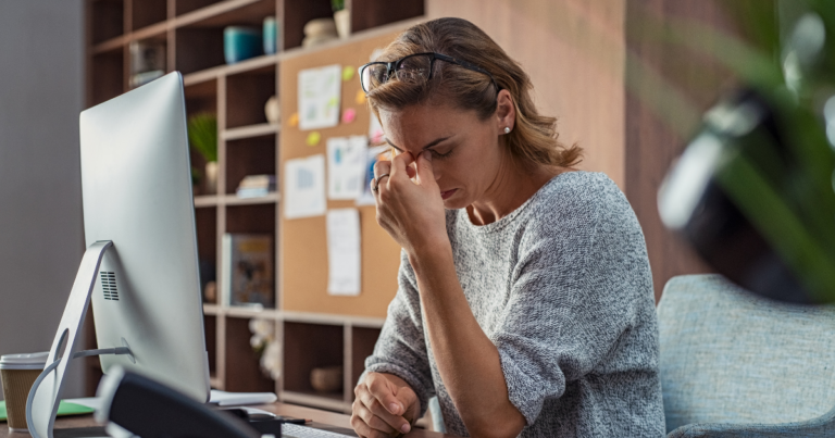stressed woman sitting at desk in front of a computer screen