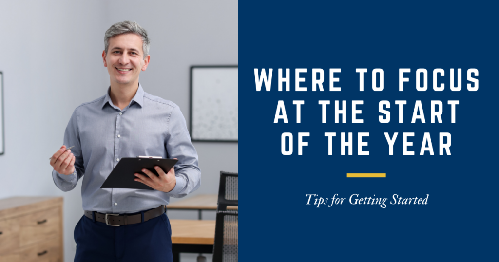 man standing with clipboard and pen in hand in an office setting with table and chair in the background